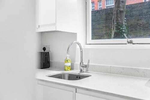 een witte keuken met een wastafel en een raam bij Security House in Londen