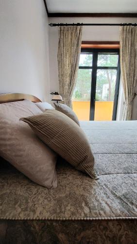 a bed with a pillow on it with a window at Villas Terrace Apartment in Praia de Mira