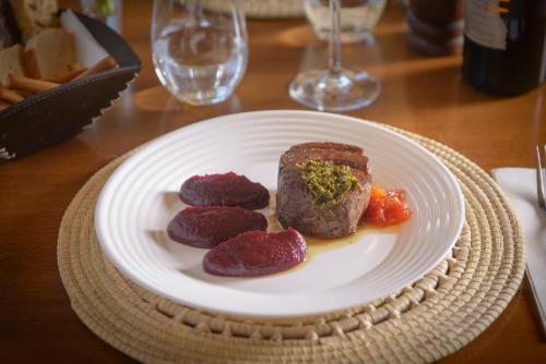 a white plate with meat and vegetables on a table at Posada Verde Oliva in Maipú