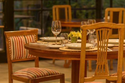 a wooden table with wine glasses and two chairs at Posada Verde Oliva in Maipú