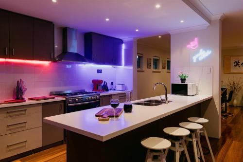 a kitchen with purple lighting and a kitchen island with stools at Waterfront Home Rockingham in Rockingham