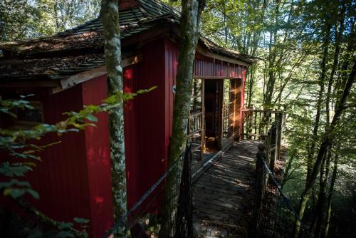 une cabane rouge dans les bois avec une passerelle en bois dans l'établissement La Cabane Zen, à Angoisse