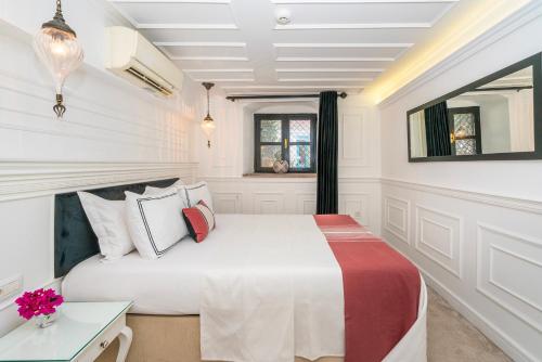 a white bedroom with a bed and a table at Siyah Lale Cunda 1841 in Cunda