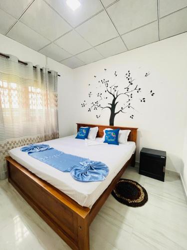 a bedroom with a bed with a tree on the wall at Kavi Villa in Weligama