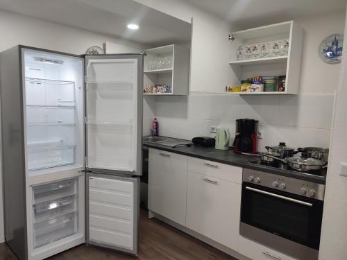 a kitchen with white cabinets and an open refrigerator at Ferienhaus Stani in Eschwege