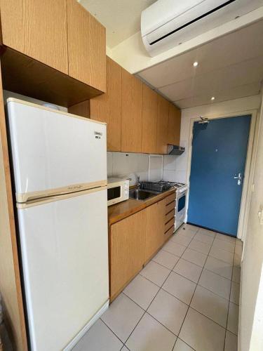 a kitchen with a white refrigerator and wooden cabinets at Loft in Siwar 2 min from Hotel Le Royal incl motor in Adūnīs