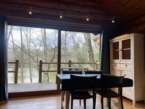 une salle à manger avec une table et des chaises et une grande fenêtre dans l'établissement Chalet avec vue sur le lac, à Angoisse
