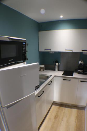 a kitchen with white cabinets and a sink and a microwave at L'Autan sage in Montgeard