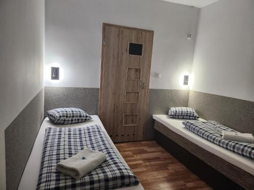 two beds in a small room with a door at Hacjenda in Radwanice