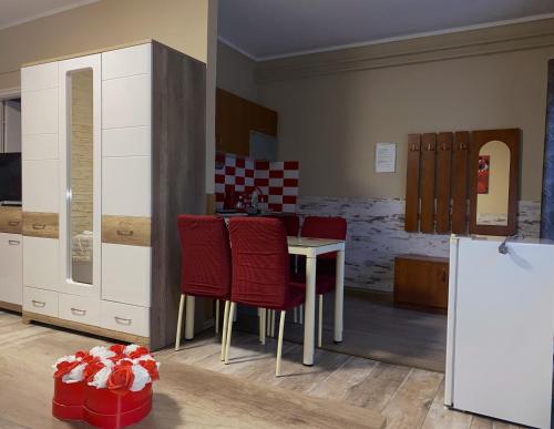 a kitchen with a table and some red chairs at Kék Lagúna Wellness Apartmanok in Egerszalók