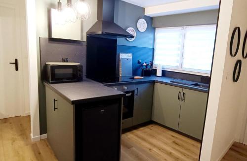 a kitchen with blue walls and a counter with a microwave at Gîte de la Halle in Vergt