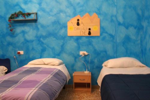 a bedroom with two beds and a blue wall at appartamento Nonna Mary in San Piero a Sieve