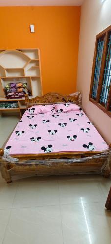 a bed with a pink comforter with cows on it at Sri Annai Home Stay I in Tiruvannāmalai