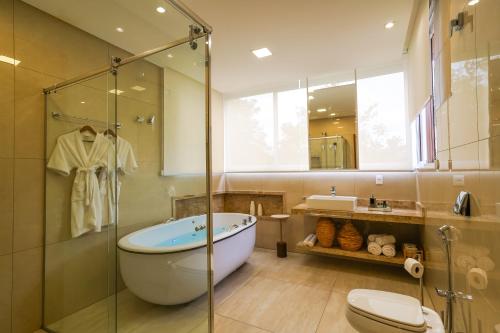 a bathroom with a tub and a glass shower at Ananda Pousada in Pirenópolis