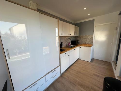 a kitchen with white cabinets and a counter top at Conteneur Design Avec Jacuzzi - Bord de Forêt in Saint-Amand-les-Eaux