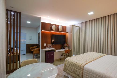a hotel room with a bed and a desk and a television at Ananda Pousada in Pirenópolis