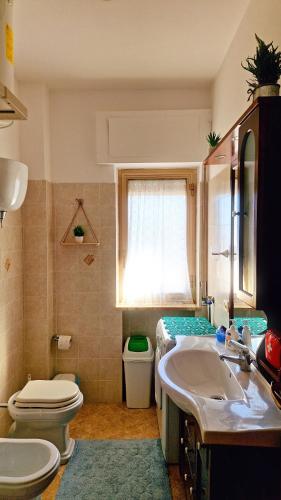a bathroom with a sink and a toilet and a window at La perla sul Tirreno in Briatico