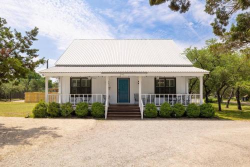 a white house with a blue door at River Access Firefly Grove Main and Guest Houses in Wimberley