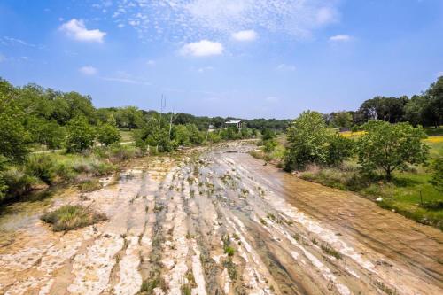 an empty dirt road in a field with trees at River Access Firefly Grove Main and Guest Houses in Wimberley