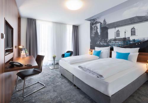 a hotel room with a large bed and a desk at Best Western Hotel am Europaplatz in Königsbrunn