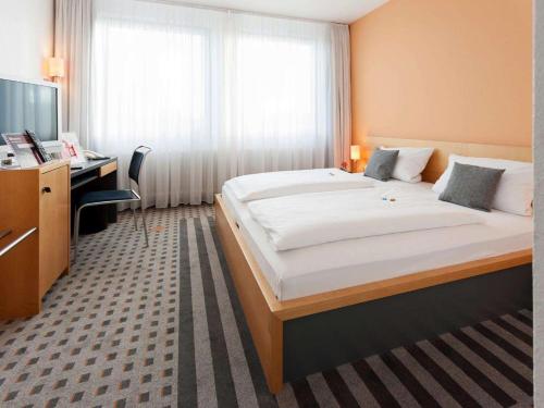 a hotel room with a large bed and a desk at Best Western Hotel am Europaplatz in Königsbrunn
