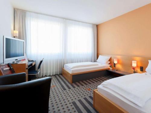 a hotel room with a bed and a television at Best Western Hotel am Europaplatz in Königsbrunn