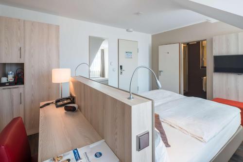 a hospital room with a bed and a desk at Best Western Hotel Breitbach in Ratingen