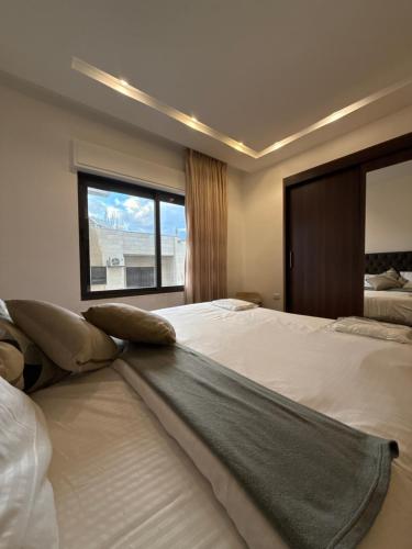 a large bedroom with two beds and a window at 3bedroom apart Deir Ghbar JRE in Amman