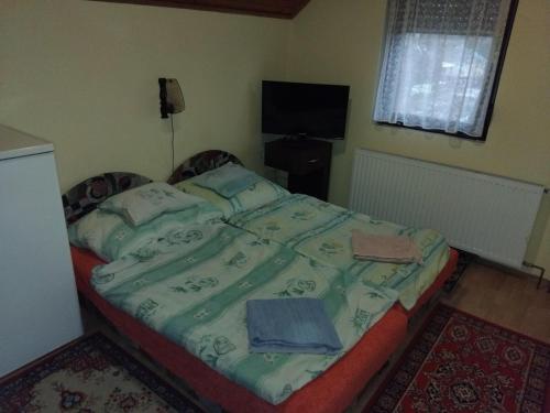a bedroom with a bed with a green comforter at Kovács vendégház in Harkány