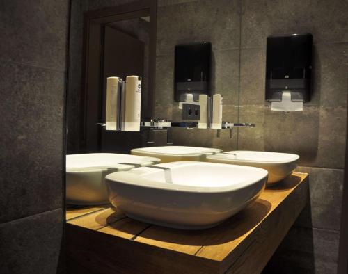 a bathroom with four white sinks and a mirror at Best Western Hotel Kaiserslautern in Kaiserslautern