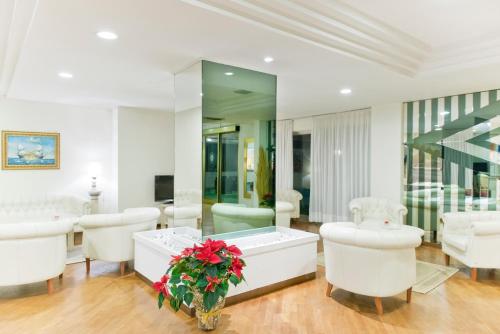 - un salon avec une baignoire et des chaises blanches dans l'établissement Hotel City, à Montesilvano