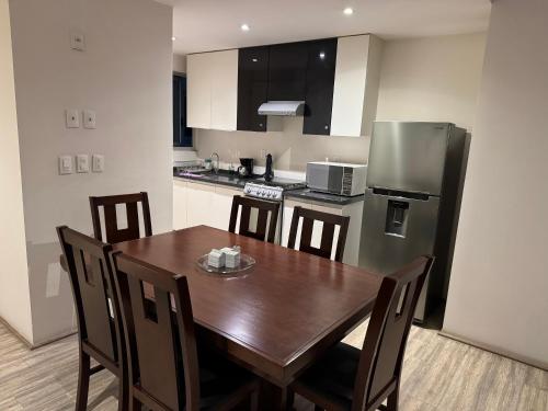 a kitchen with a wooden table and a refrigerator at Increíble alojamiento en Santa Fe, CDMX con alberca, gym y estacionamiento in Mexico City