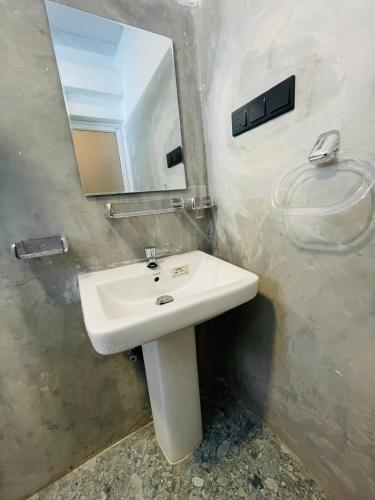 a bathroom with a white sink and a mirror at Serandib Beach Villa in Weligama