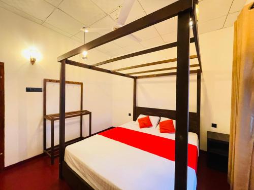a bedroom with a bunk bed with red and white sheets at Serandib Beach Villa in Weligama