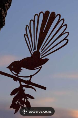 a bird with its wings out is sitting on a branch at Fantail Cottage in Hamilton