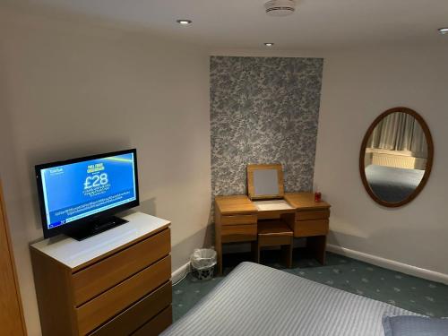 a bedroom with a tv on a dresser and a desk at Quince House in Oxford