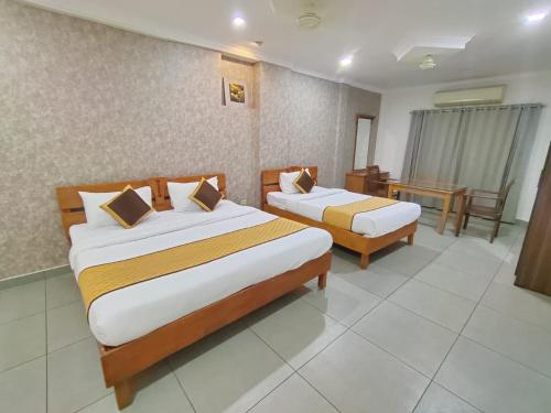 a hotel room with two beds and a table at Holidays Garden Resort in Kalpetta