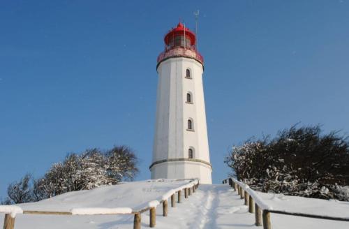 a lighthouse covered in snow on a snow covered pier at Ferienwohnungen Albrecht in Kloster
