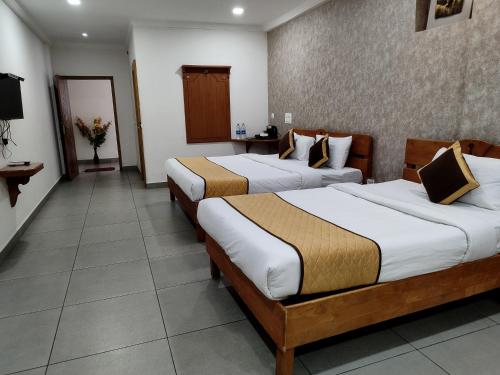 a hotel room with two beds in a room at Holidays Garden Resort in Kalpetta