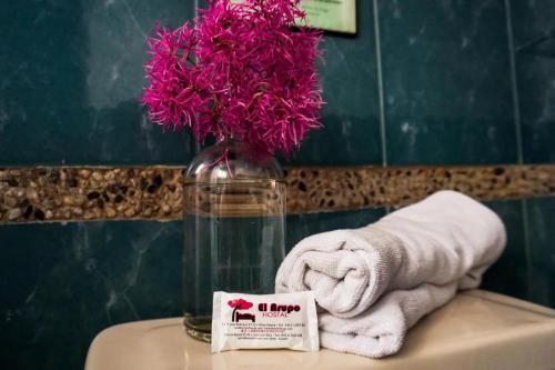 a bathroom with a towel and a vase with pink flowers at Casa del Arupo B&B in Quito