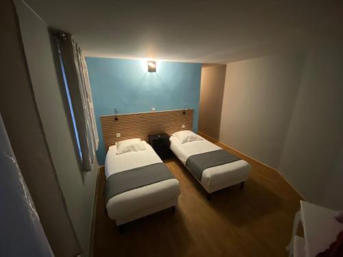 two beds in a small room with a blue wall at Royal Haveli in Tergnier