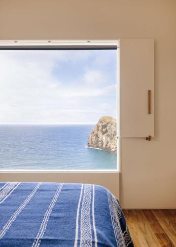a bedroom with a large window overlooking the ocean at The Blue House Azores in Capelas