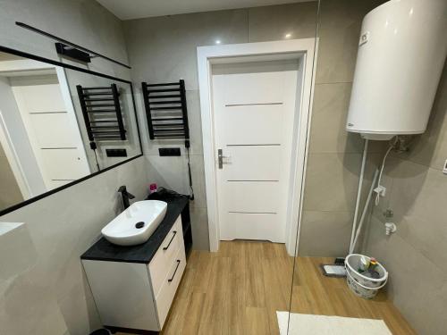 a bathroom with a sink and a white door at Biały Domek Świerczek in Słopnice