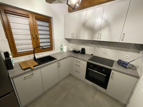 a kitchen with white cabinets and a sink and a window at Biały Domek Świerczek in Słopnice