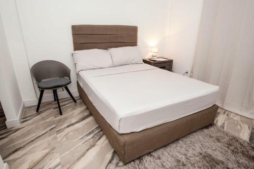 a small bedroom with a bed and a chair at Maximum Beach Hotel in Corozal