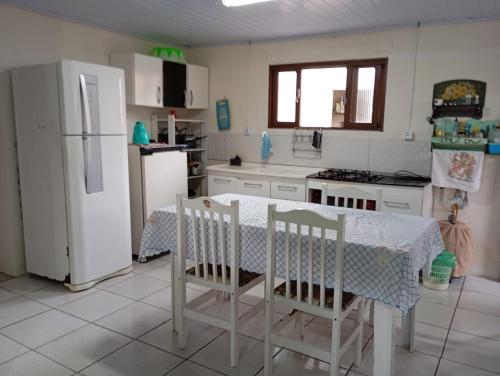 a kitchen with a table and a white refrigerator at Casa Amarela in São Francisco do Sul