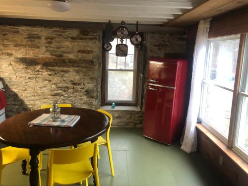 a dining room with a table and yellow chairs and a red refrigerator at Relax Like It's 1800! in Pond Eddy