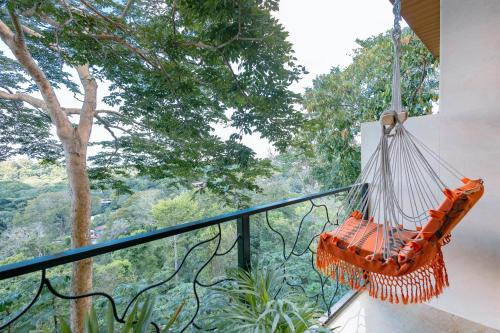 an orange hammock hanging from a balcony with trees at Mountain Top Park Hotel in Quepos