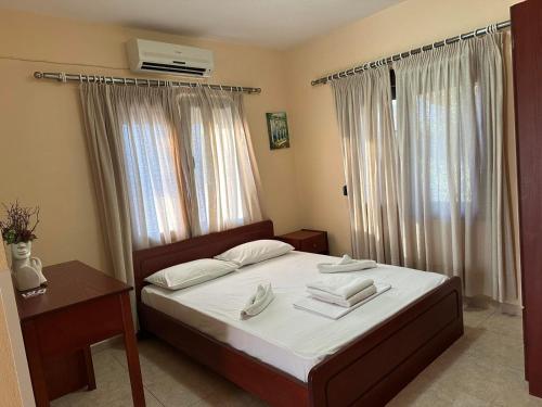 Schlafzimmer mit einem Bett mit weißer Bettwäsche und einem Tisch in der Unterkunft VILLA ELENI in Skala Marion