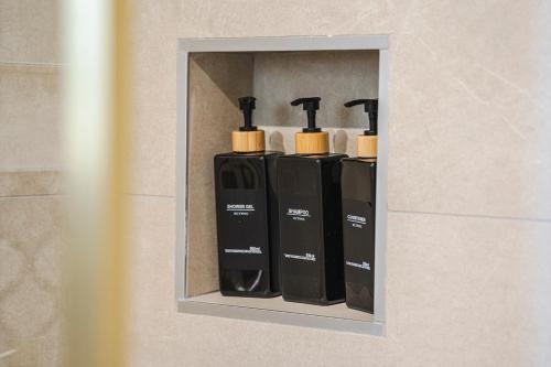 a wall mounted shelf with four black and white bottles at Chambres hote Le Clos 26 in Bellerive-sur-Allier